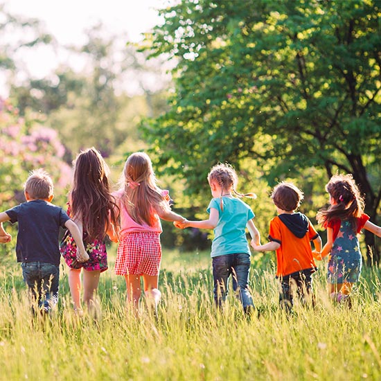 Group of kids running through sunny field